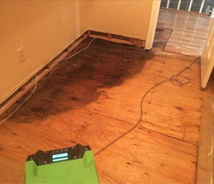 Sub floor exposed in a room with drying equipment drying out a wet spot on the floor.