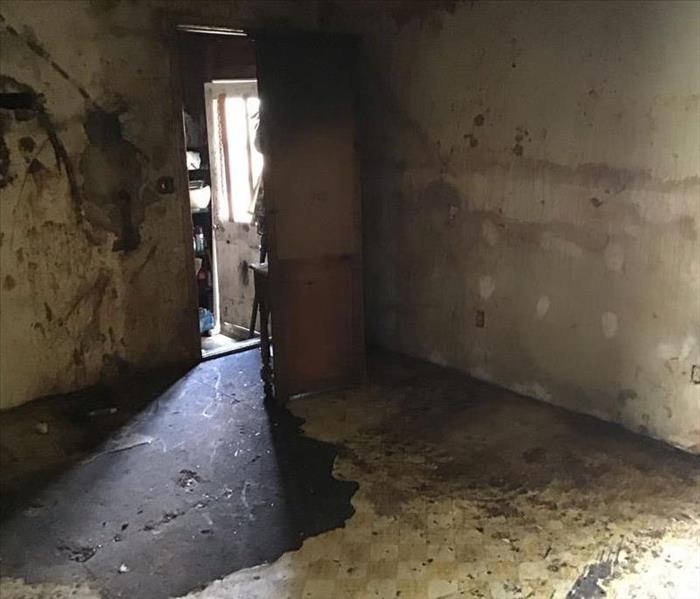 Room with a view of a doorway after a fire damage.  The walls and floors are completely distroyed.