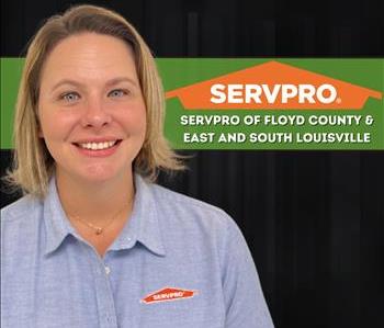 Woman wearing a SERVPRO shirt standing in front of a black background and a SERVPRO logo